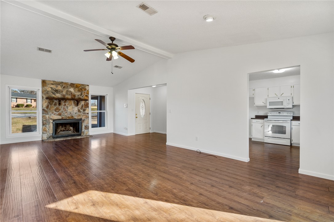 2305 Millgate Road Anderson, SC 29621 - Photo 5 of 18 A spacious living area with warm wood flooring and a floor-to-ceiling stone fireplace.