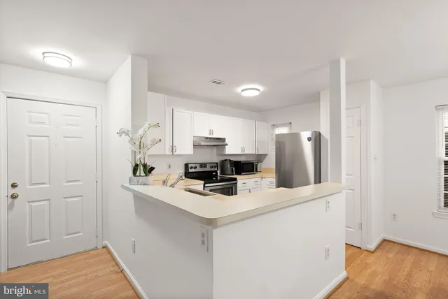 a kitchen with stainless steel appliances a refrigerator a stove a sink and white cabinets