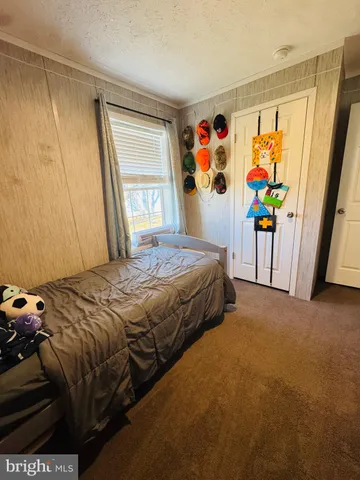 a bedroom with a bed painting on the wall and a window