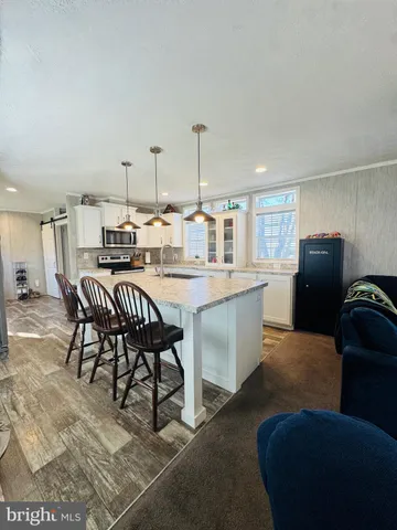 a kitchen with stainless steel appliances kitchen island granite countertop a sink a stove a dining table and chairs