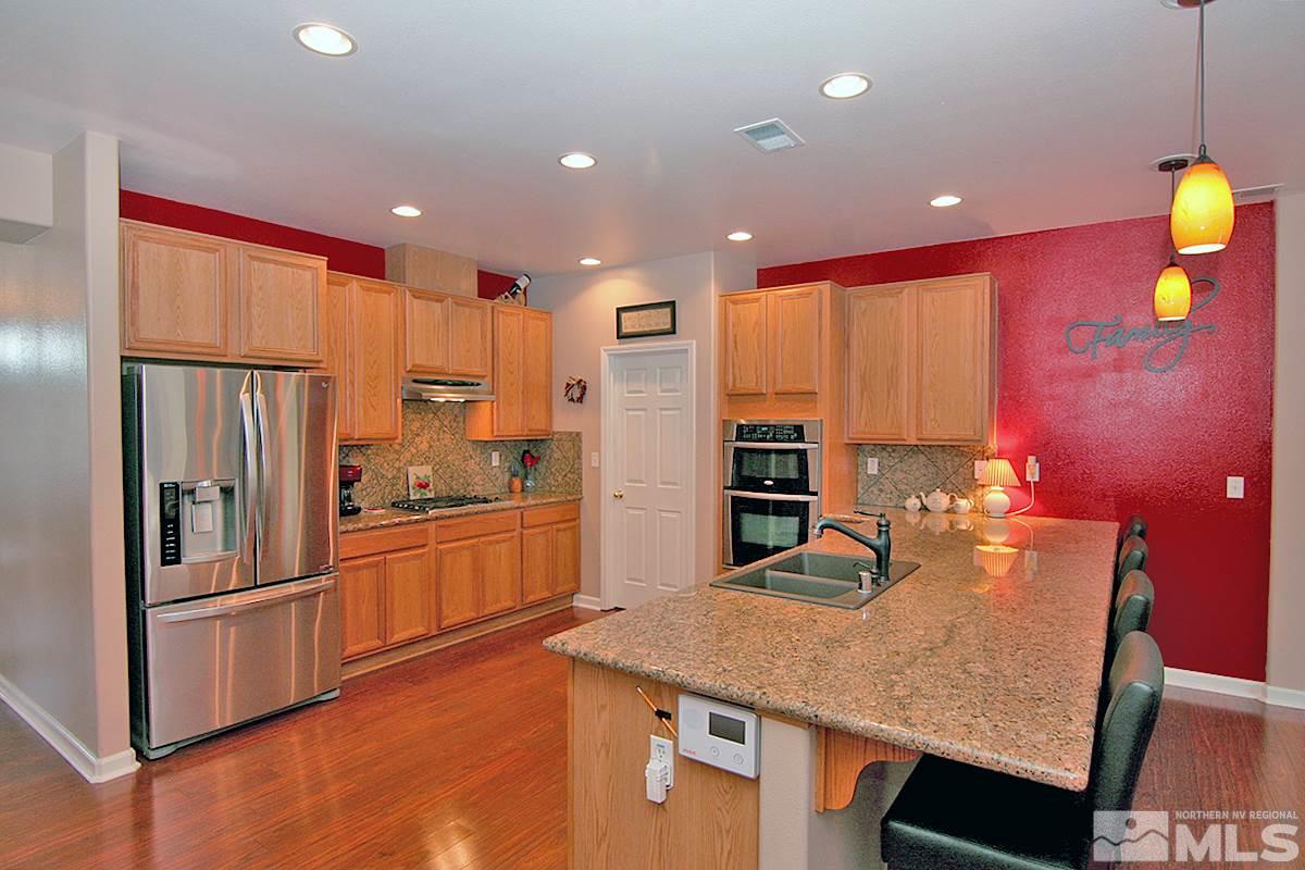 10860 Rushing Flume Drive Reno, NV 89521 - Photo 4 of 23 a kitchen with stainless steel appliances granite countertop a sink refrigerator and microwave