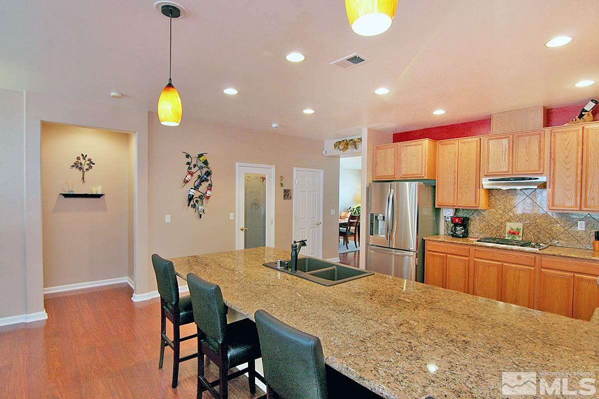 10860 Rushing Flume Drive Reno, NV 89521 - Photo 5 of 23 a kitchen with stainless steel appliances granite countertop a kitchen island a stove a dining table and chairs with wooden floor