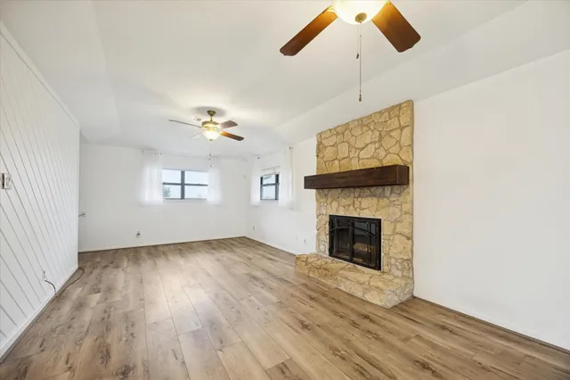 a view of an empty room with window and wooden floor