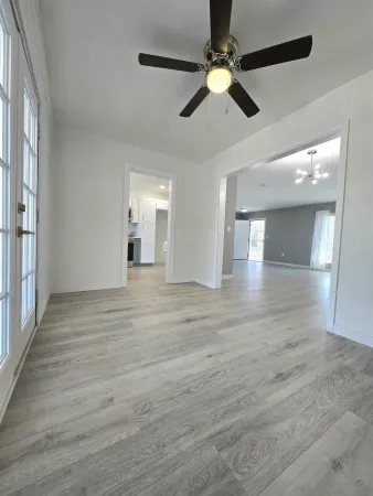 an empty room with wooden floor fan and windows