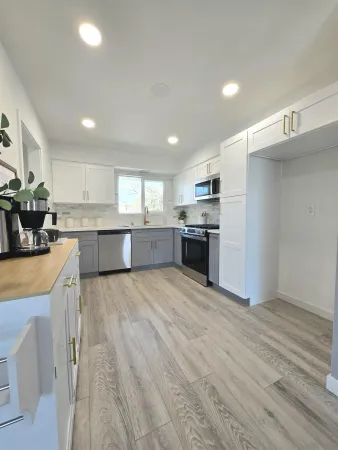 a large kitchen with kitchen island a stove a refrigerator a sink dishwasher and a oven with wooden floor
