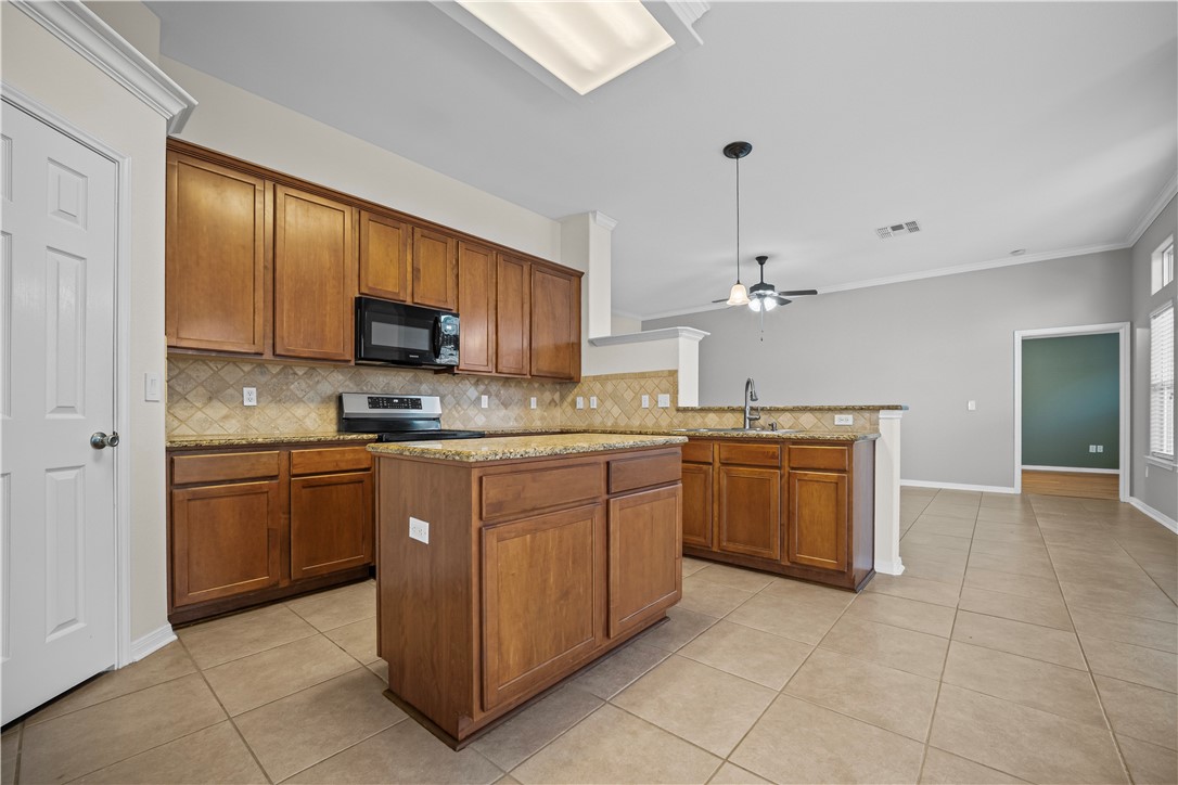 7509 Exeter Corpus Christi, TX 78414 - Photo 8 of 29 a kitchen with kitchen island granite countertop a stove top oven a sink dishwasher and a refrigerator with wooden cabinets