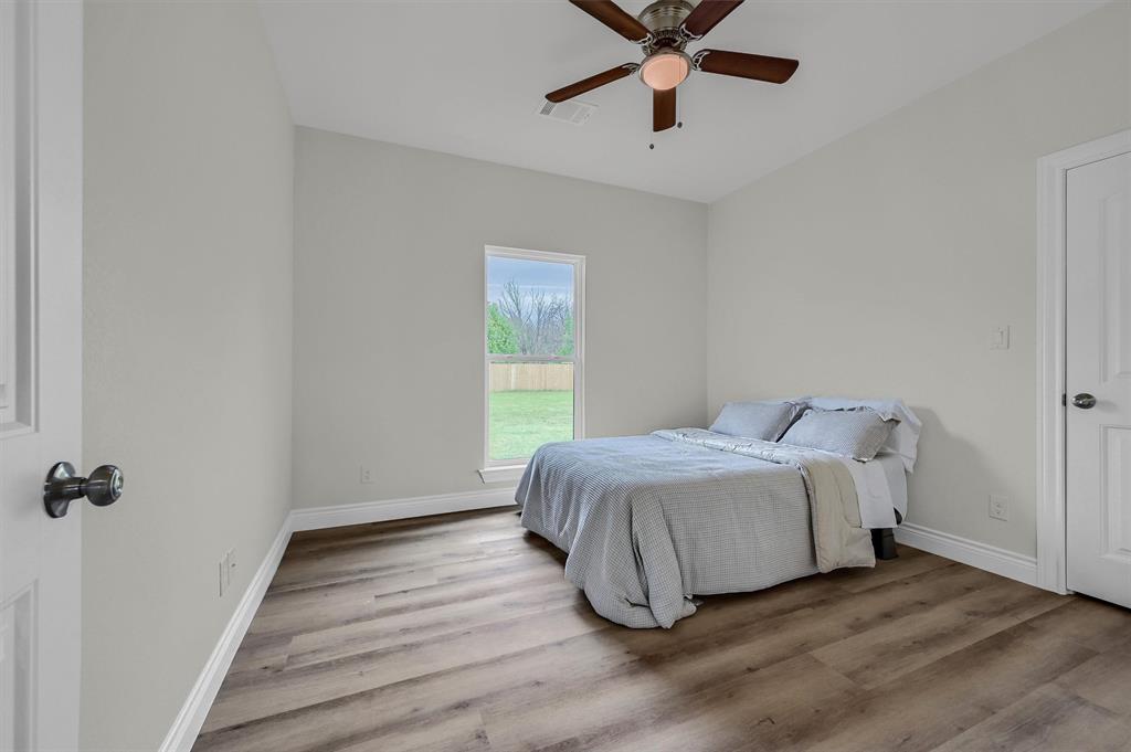 25 Pear Tree Lane Collinsville, TX 76233 - Photo 25 of 34 a bedroom with a bed and wooden floor