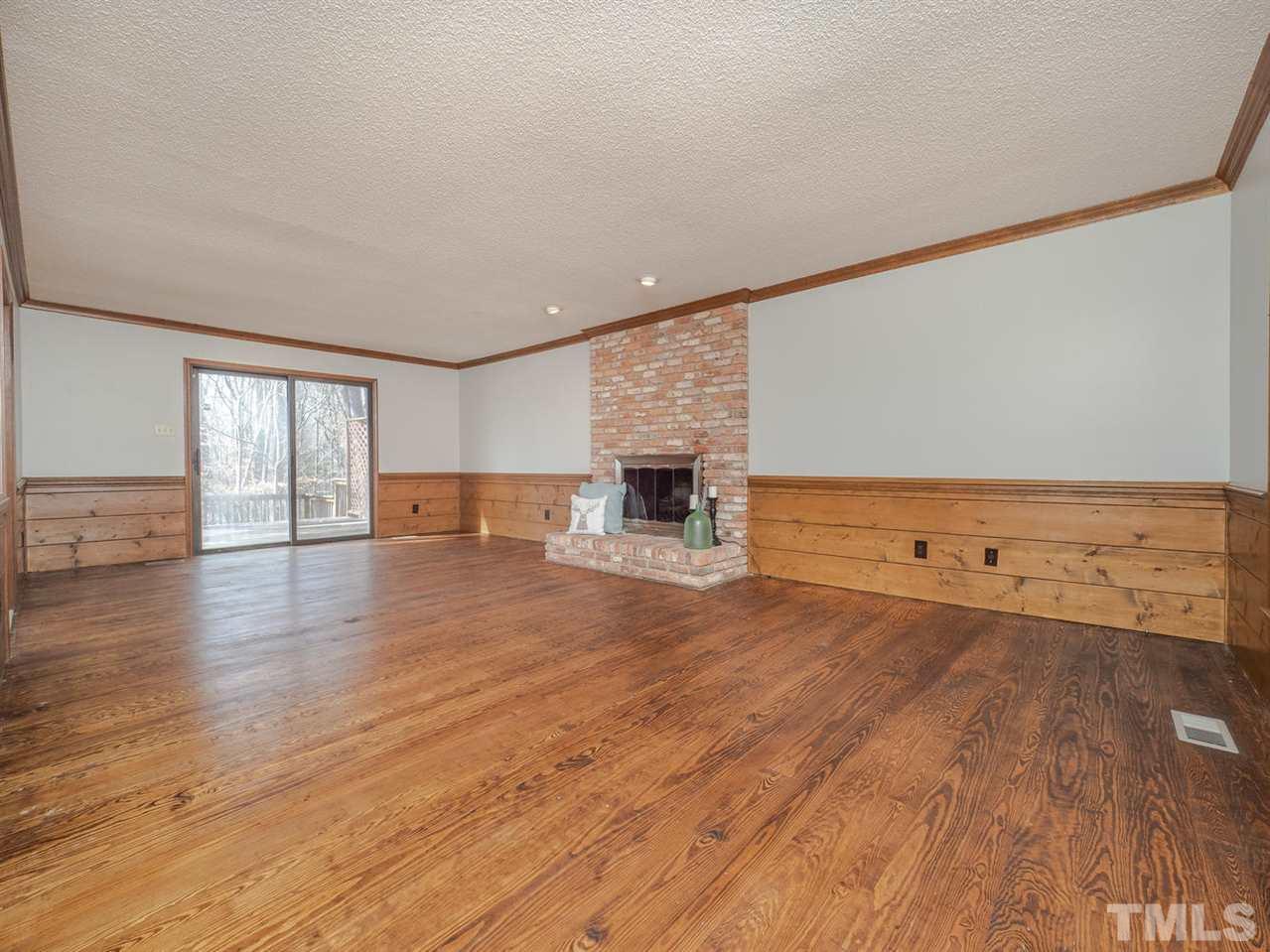 8317 Druids Lane Raleigh, NC 27613 - Photo 6 of 24 Family room runs the length of the house, with gorgeous heart pine floors, a masonry fireplace, tons of moldings and sliding door access to the backyard.