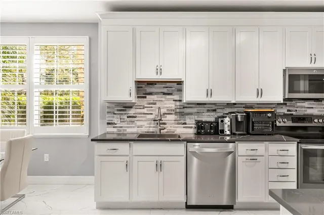 a kitchen with stainless steel appliances granite countertop a stove a sink and white cabinets