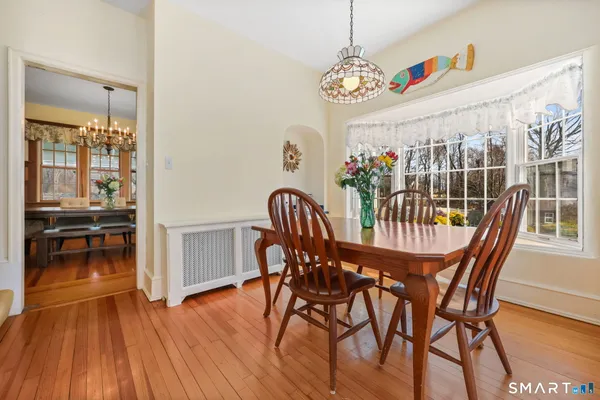 a kitchen with stainless steel appliances granite countertop a refrigerator a microwave oven dining table and chairs with wooden floor