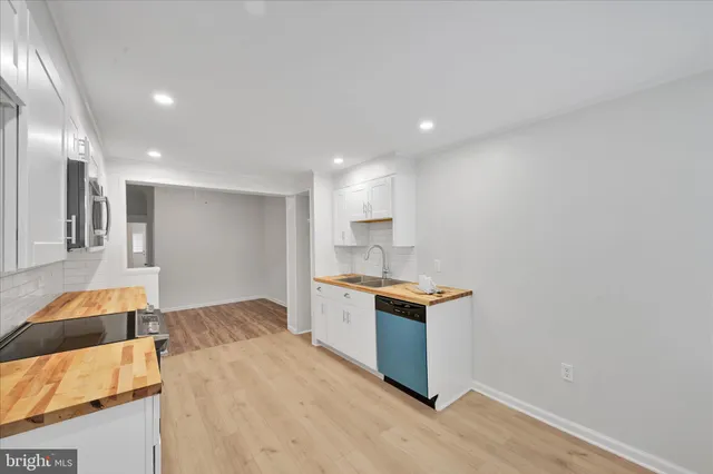 a open kitchen with white cabinets and wooden floor