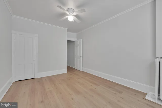 an empty room with wooden floor and ceiling fan