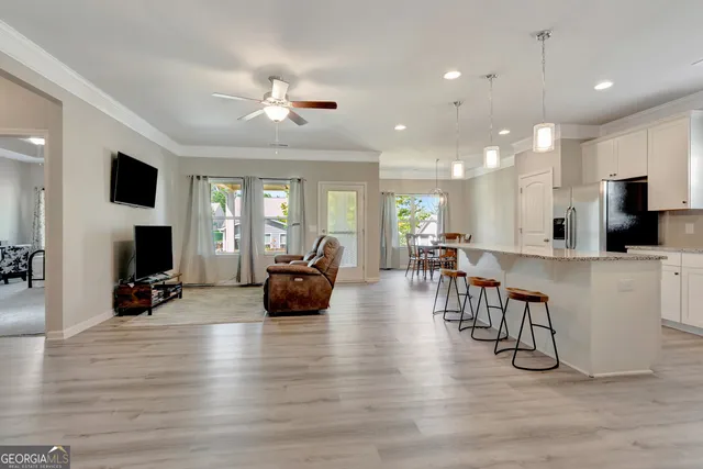 a living room with furniture kitchen view and a wooden floor