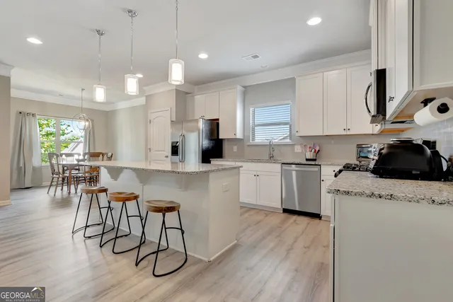 a kitchen with granite countertop a table chairs stove microwave and cabinets with wooden floor