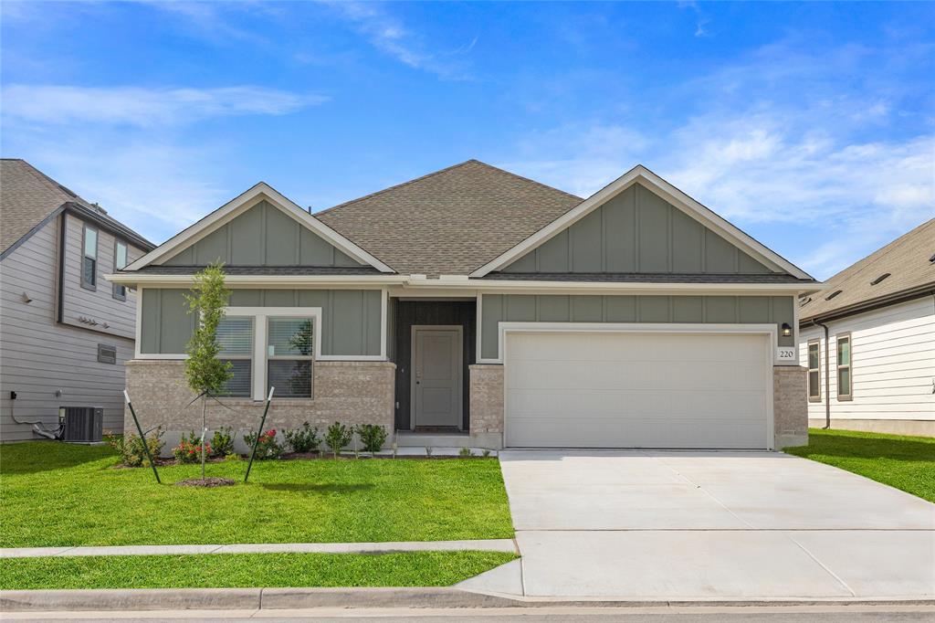 Craftsman inspired home featuring board and batten siding, brick siding, a front lawn, roof with shingles, and concrete driveway