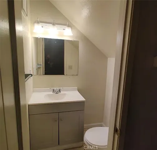 a bathroom with a toilet a sink a mirror and vanity