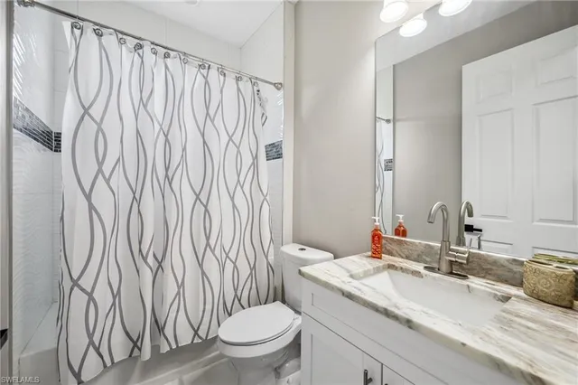 a bathroom with a granite countertop sink and a toilet