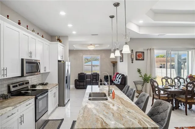 a kitchen with stainless steel appliances kitchen island granite countertop a stove a sink a refrigerator and chairs
