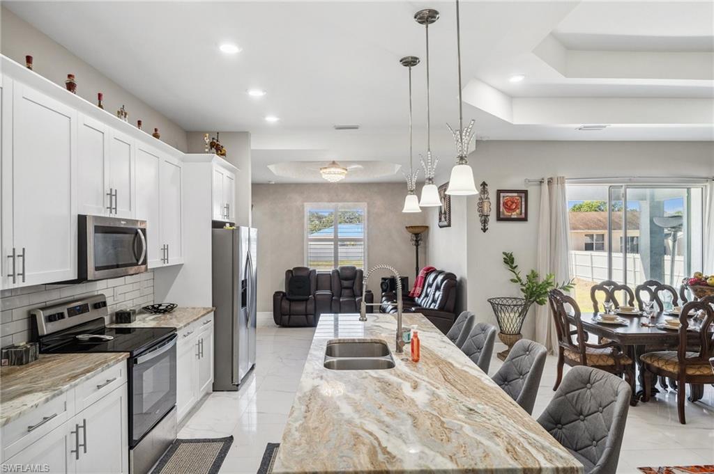 3407 20th Street Southwest Lehigh Acres, FL 33976 - Photo 9 of 23 a kitchen with stainless steel appliances kitchen island granite countertop a stove a sink a refrigerator and chairs