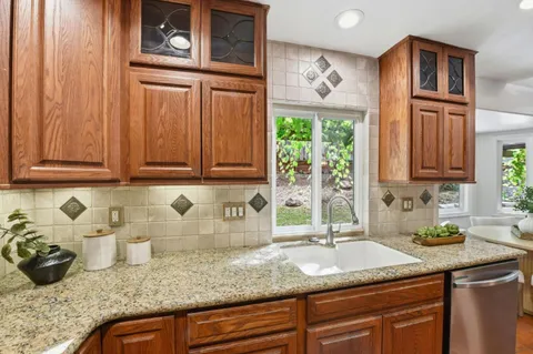 a kitchen with granite countertop a sink a stove and cabinets