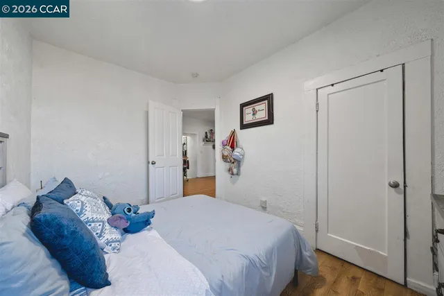 an empty room with wooden floor closet and windows