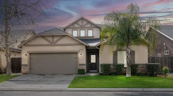 a front view of a house with a yard and potted plants