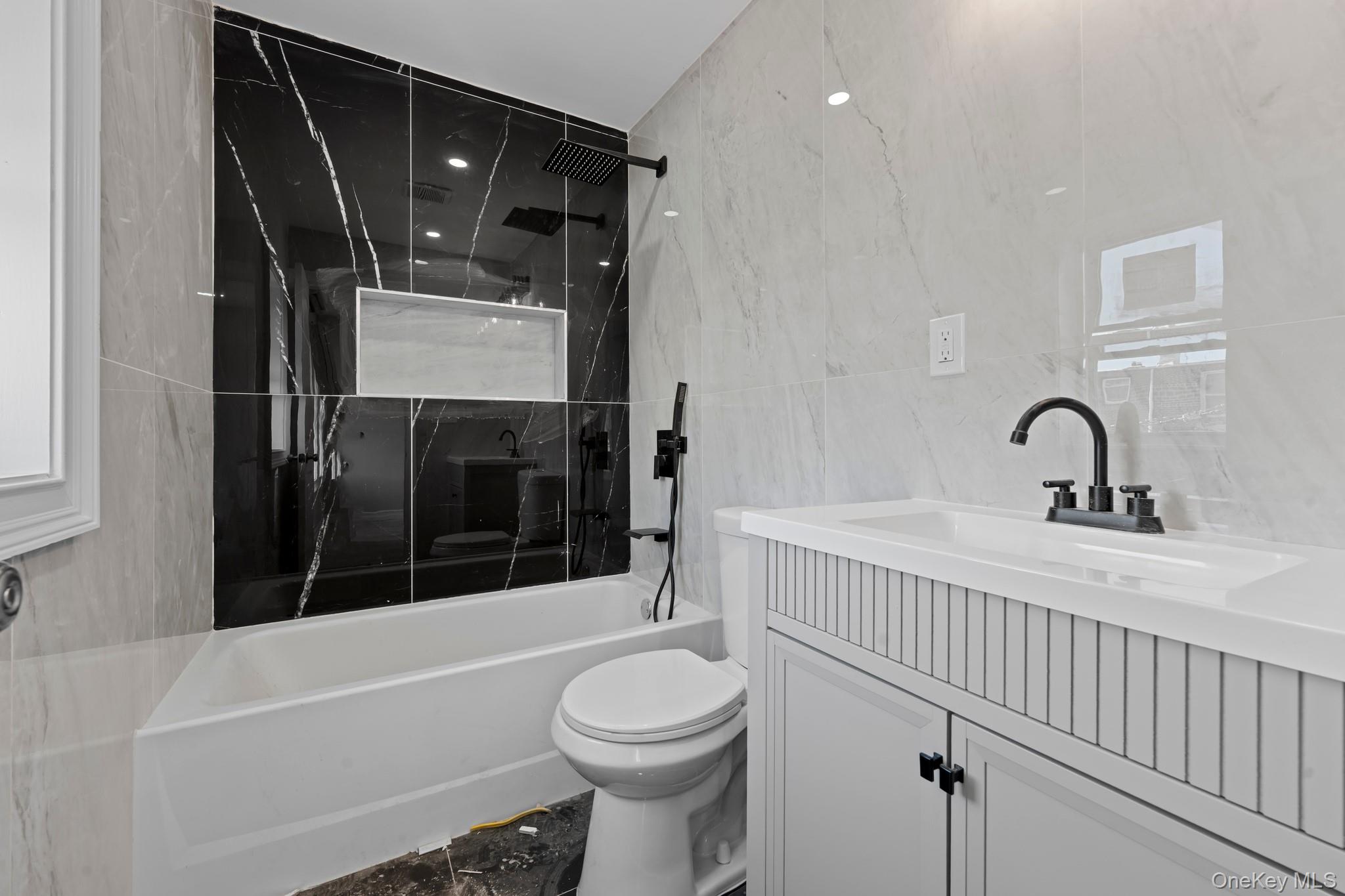 179-18 Selover Road Queens, NY 11434 - Photo 11 of 18 Bathroom with a combined bath / shower with marble appearance, tile walls, vanity, and stone wall