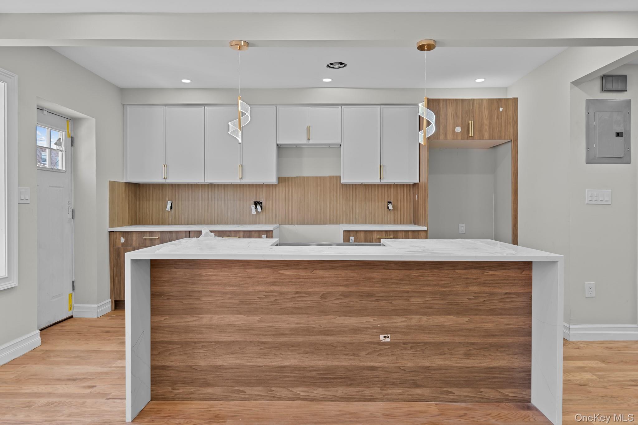 179-18 Selover Road Queens, NY 11434 - Photo 2 of 18 Kitchen featuring white cabinetry, light wood-type flooring, electric panel, light stone countertops, and pendant lighting