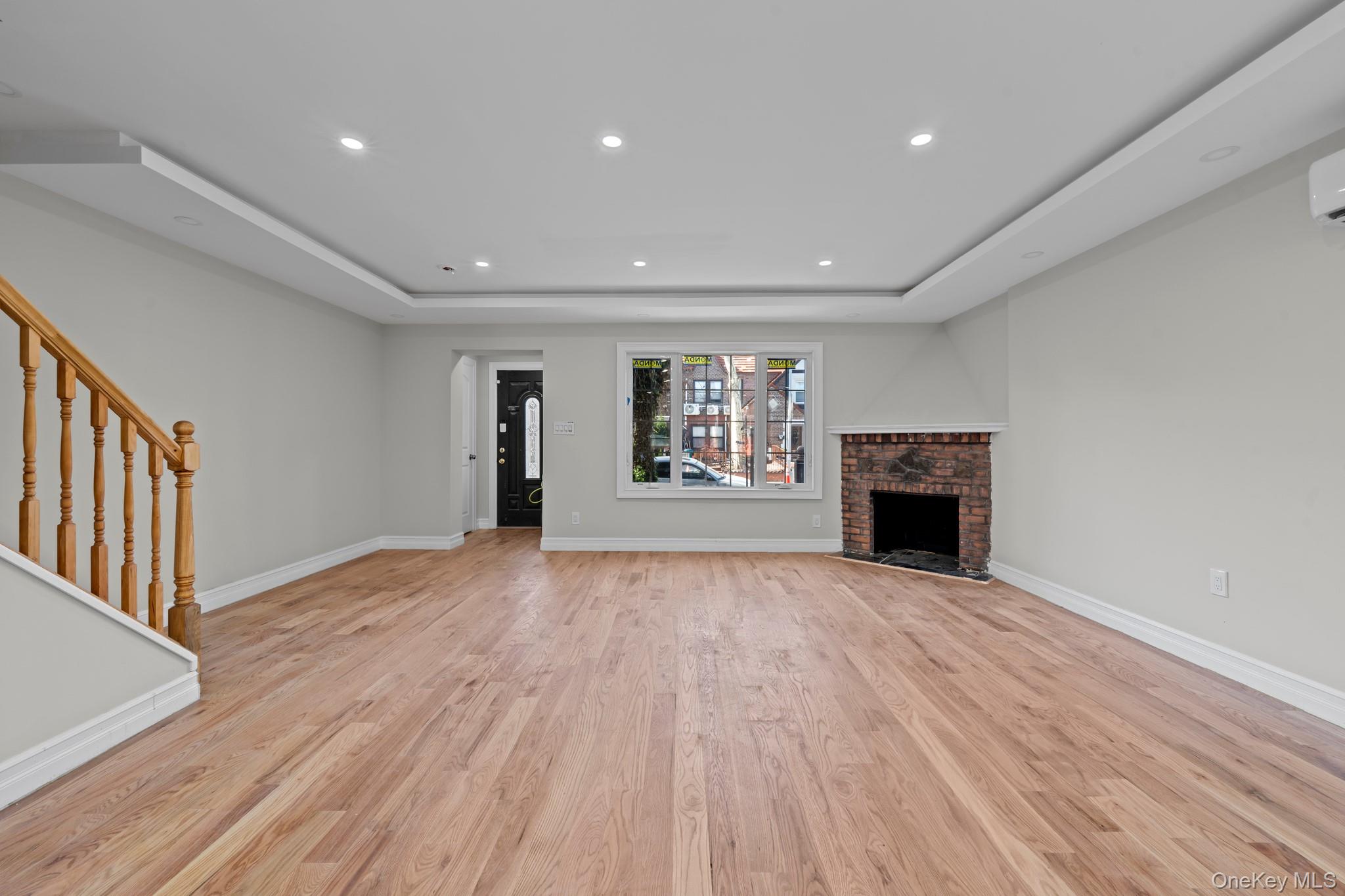 179-18 Selover Road Queens, NY 11434 - Photo 4 of 18 Unfurnished living room with a raised ceiling, stairs, a brick fireplace, light wood-type flooring, and recessed lighting