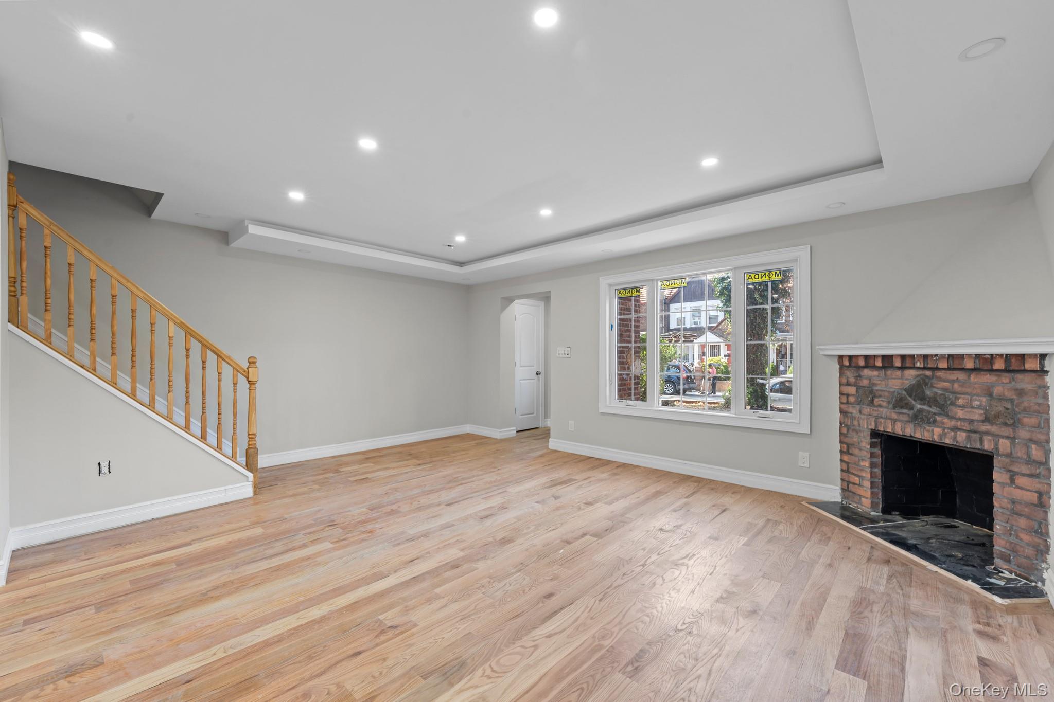 179-18 Selover Road Queens, NY 11434 - Photo 6 of 18 Unfurnished living room featuring recessed lighting, light wood finished floors, a raised ceiling, a fireplace, and stairs