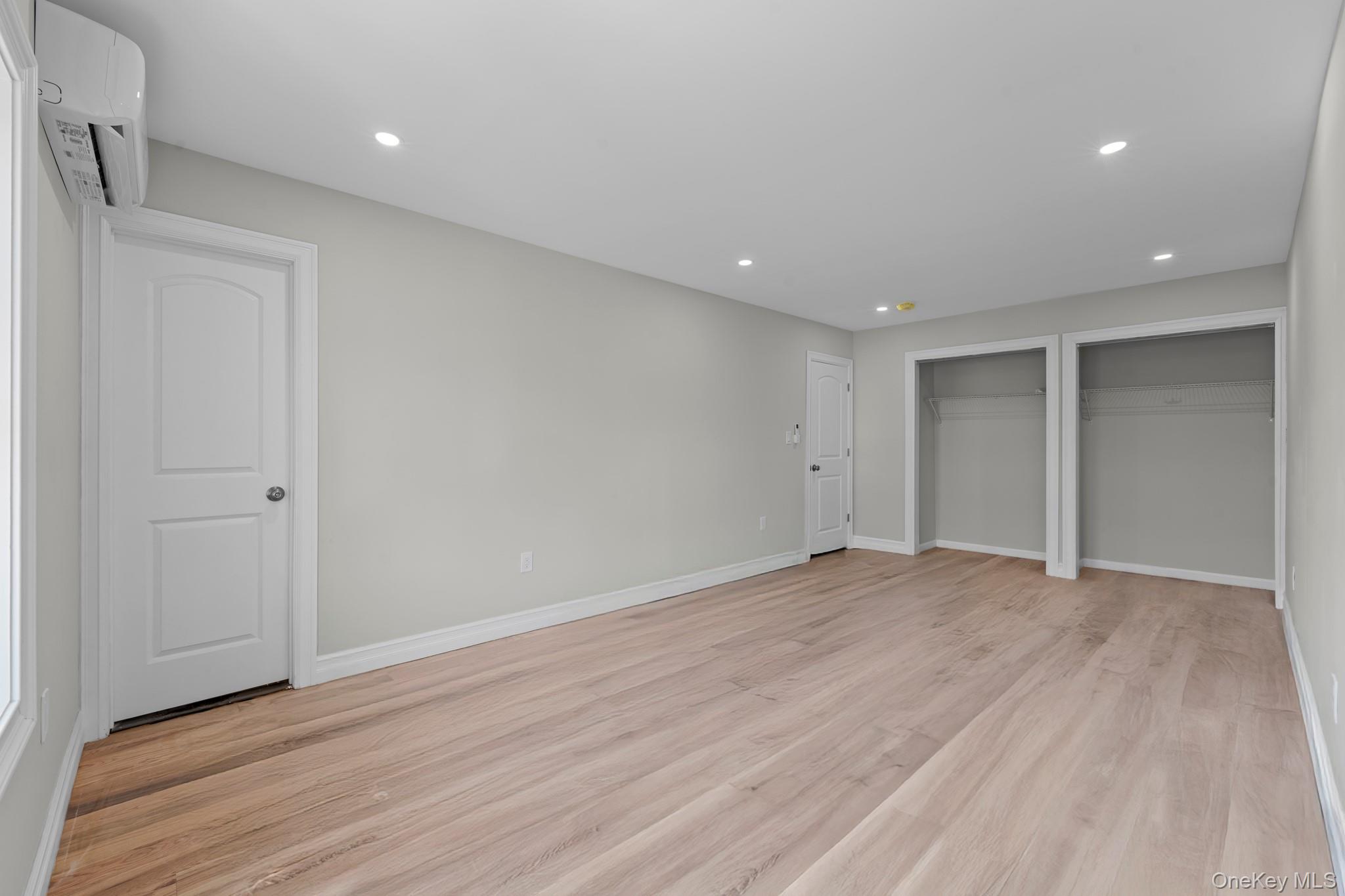 179-18 Selover Road Queens, NY 11434 - Photo 10 of 18 Unfurnished bedroom with two closets, light wood finished floors, recessed lighting, and a wall unit AC