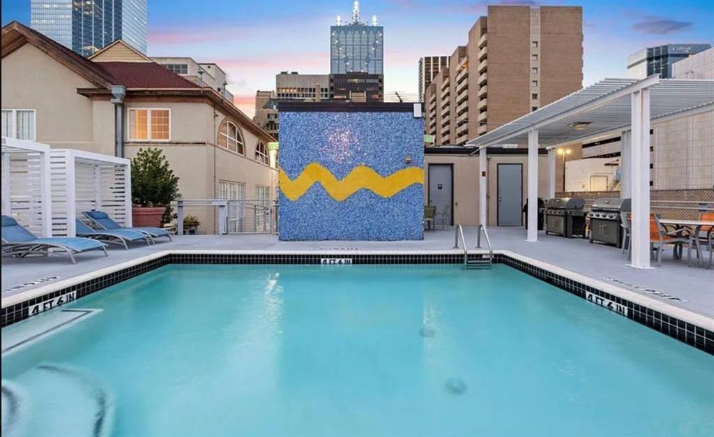1122 Jackson Street, Unit 514 Dallas, TX 75202 - Photo 32 of 40 Outdoor swimming pool featuring a tiled accent wall, surrounding lounge seating, and a covered grilling area