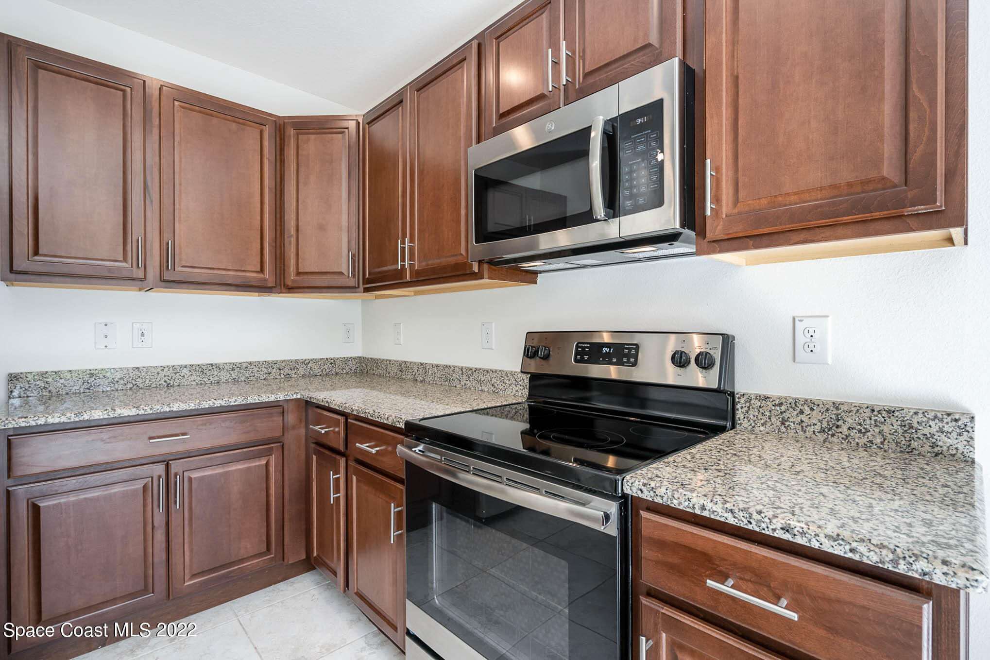 1061 Wabash Road Southeast Palm Bay, FL 32909 - Photo 8 of 22 a kitchen with granite countertop a sink dishwasher stove and microwave with wooden cabinets