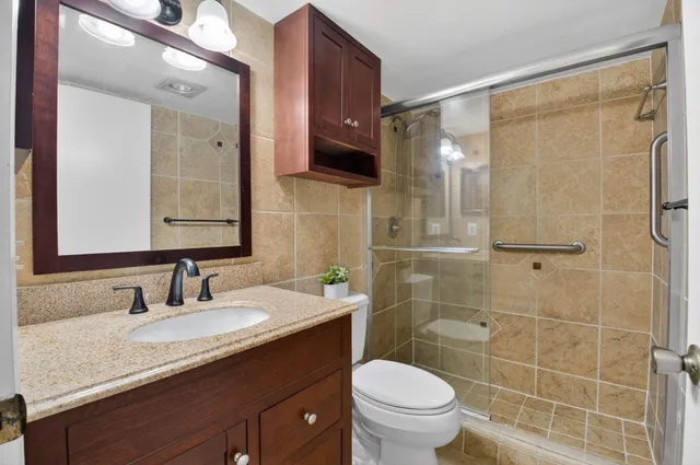 a bathroom with a granite countertop sink toilet and shower