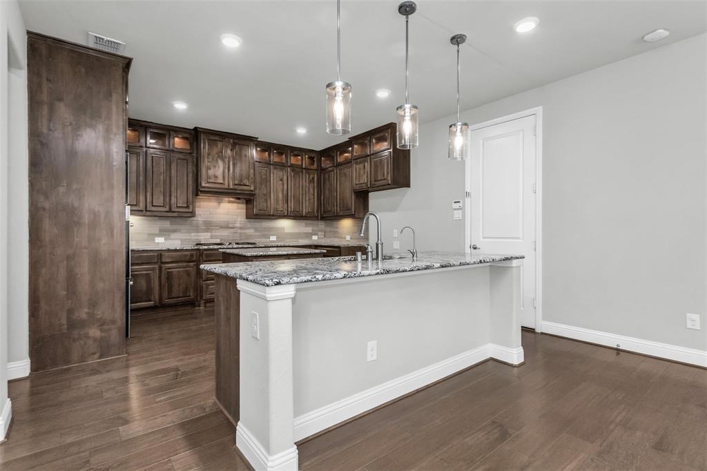 6333 Hall Road Frisco, TX 75034 - Photo 14 of 38 Kitchen featuring dark wood cabinetry, granite countertops, tile backsplash, and wood-finish flooring