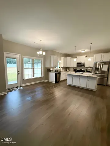 an open kitchen with kitchen island wooden floors and stainless steel appliances