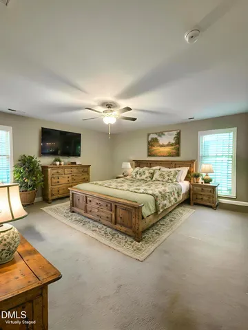 a spacious bedroom with a bed and a flat tv screen on dresser