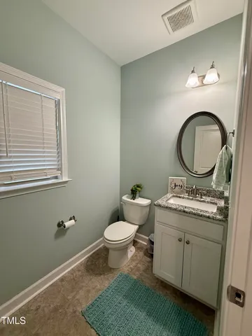 a bathroom with a granite countertop toilet a sink and a mirror