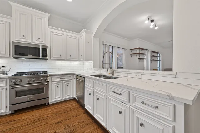 a kitchen with stainless steel appliances granite countertop a stove and white cabinets