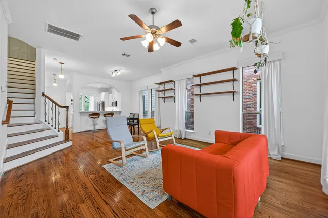 a living room with furniture kitchen view and a wooden floor