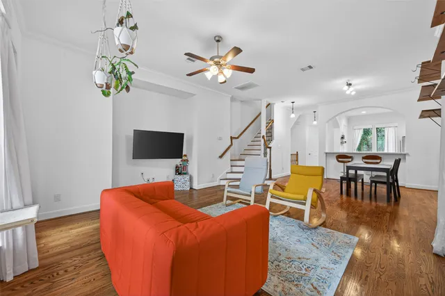 a living room with couches a coffee table and a flat screen tv with wooden floor