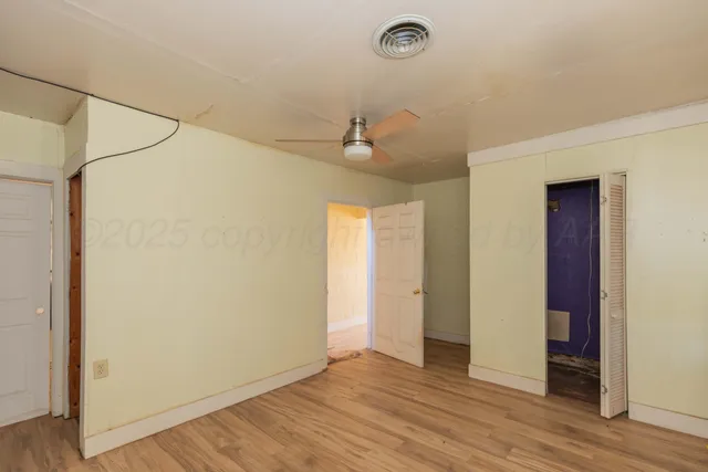 a view of a room with wooden floor and a ceiling fan