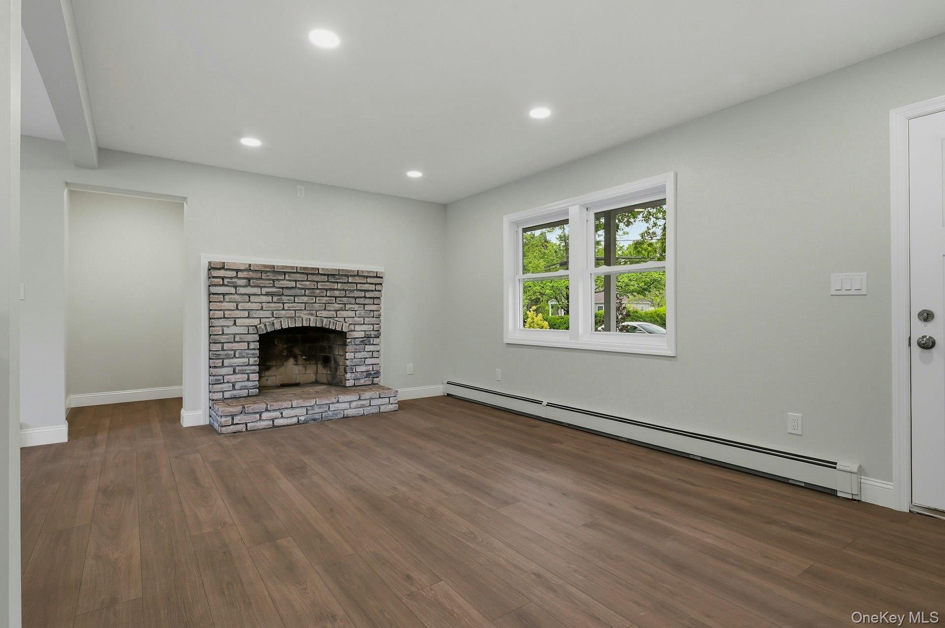 101 Rustic Road Centereach, NY 11720 - Photo 17 of 42 an empty room with wooden floor a fireplace and windows