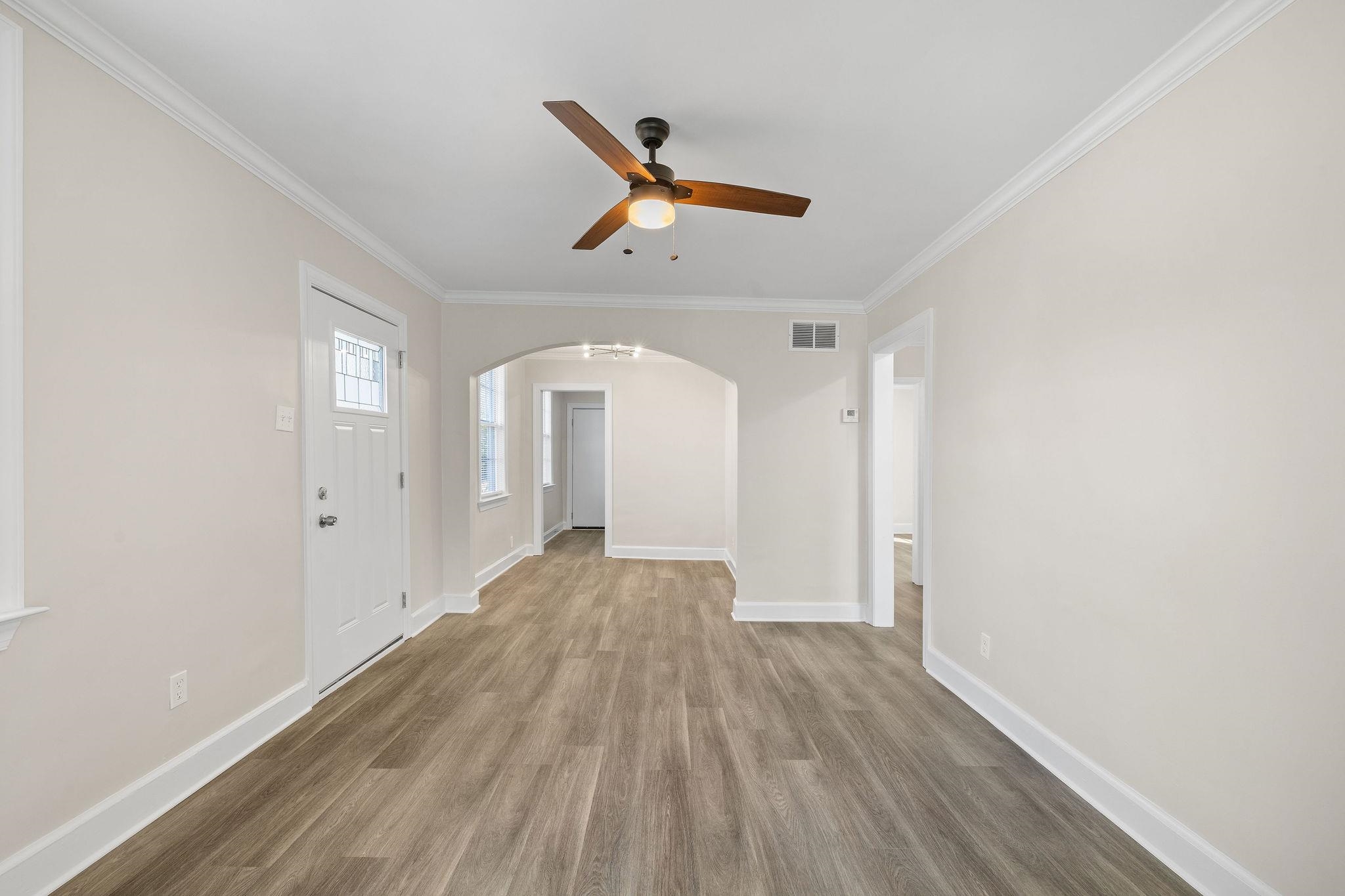 1120 Parkland Road Memphis, TN 38111 - Photo 10 of 23 Unfurnished living room with arched walkways, crown molding, wood finished floors, and a ceiling fan