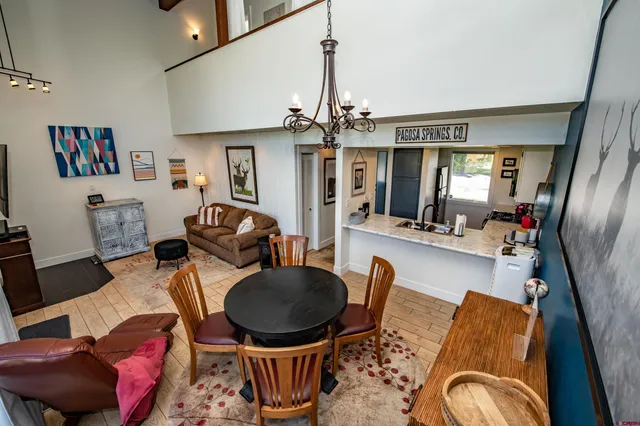 a living room with furniture a chandelier and wooden floor