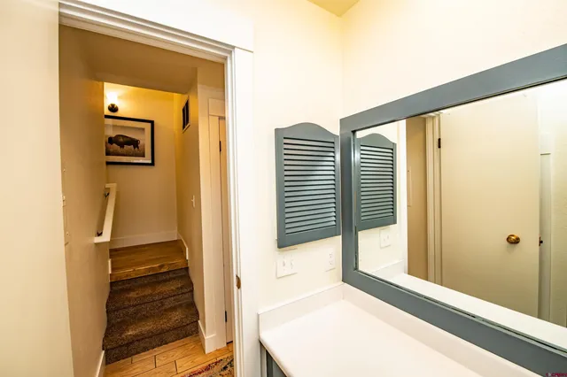 a view of a hallway with wooden floor and a bathroom