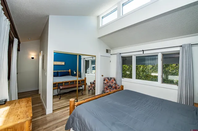 a bed room with wooden floor and windows