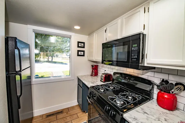 a kitchen with stainless steel appliances a stove a sink and a refrigerator with wooden floor