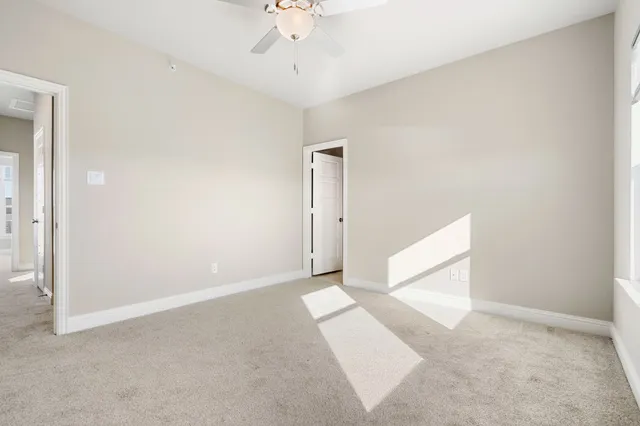 an empty room with a chandelier fan and windows