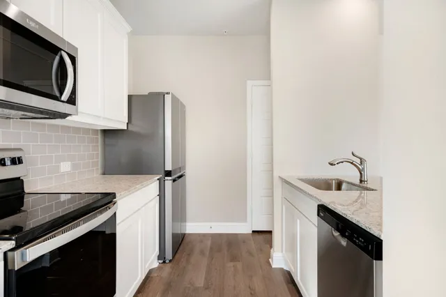 a kitchen with granite countertop a sink stove and refrigerator